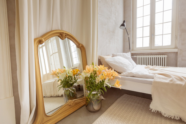 Udobna spavaća soba sa velikim krevetom i ogledalom sa zlatnim ramom